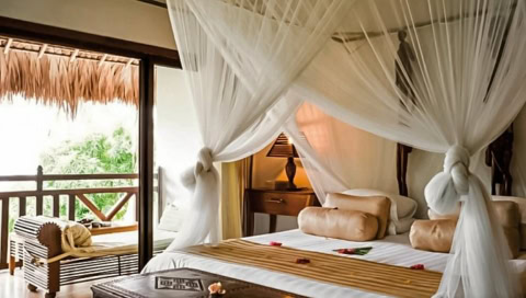 Doppelbett mit weißen Laken und Vorhängen.