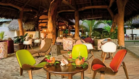 Überdachte offene Bar mit kleinen Tischen und Sesseln direkt am Strand im Sand.