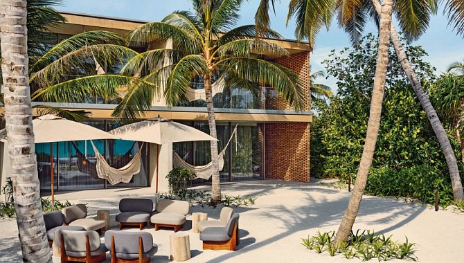 Moderner Loungebereich am Strand mit Sitzgruppe, Hängematten und Palmen vor der Villa