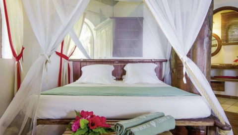 Doppelbett mit Weißen Laken und Vorhängen.