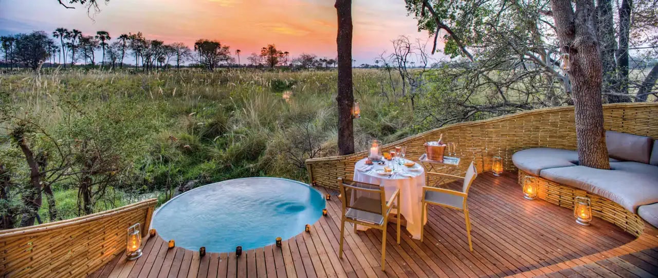 Terrasse mit Pool und romantisch gedecktem Tisch bei Sonnenuntergang mit Blick auf die Natur.
