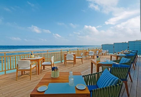 Hotelrestaurant auf Veranda mit Meerblick. Gedeckte zweiertische aus Holz