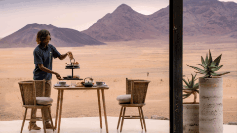 Servierte Frühstückstafel auf der Terrasse mit Wüstenblick und Bergen im Hintergrund