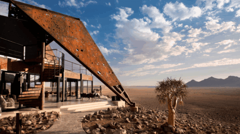 Architektonisch markante Lodge mit rostfarbenem Dach und weitem Wüstenpanorama