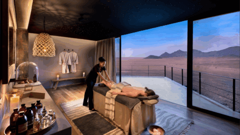 Spa-Behandlungsraum mit Massage und Blick auf die Wüste durch große Glasfront