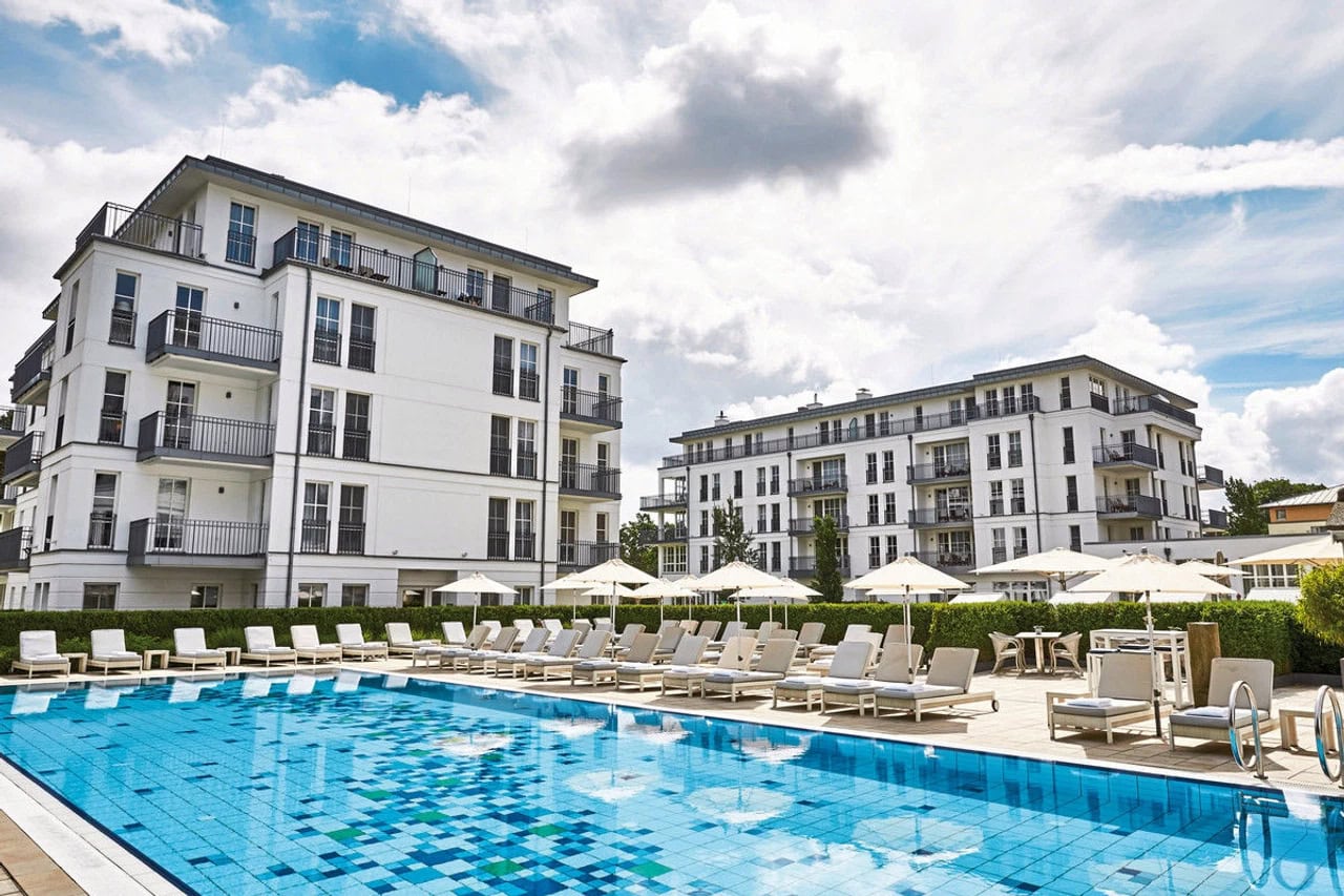 Außenpool im Steigenberger Grandhotel & Spa Heringsdorf mit Sonnenliegen, Sonnenschirmen, weißer Hotelfassade und ruhiger Resortatmosphäre