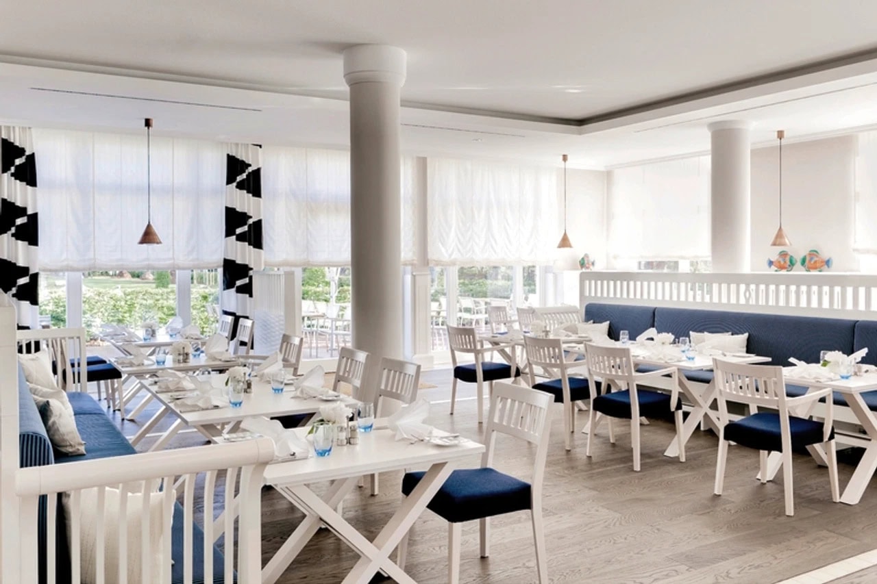 Helles Restaurant im Steigenberger Grandhotel & Spa Heringsdorf mit weißen Tischen, blauen Sitzpolstern, großen Fenstern und maritimem Einrichtungskonzept