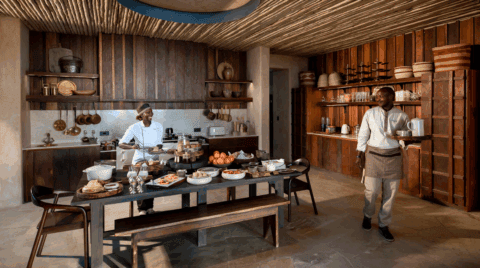 Frühstückszubereitung in rustikaler Lodgeküche mit frischen Früchten und herzlicher Atmosphäre