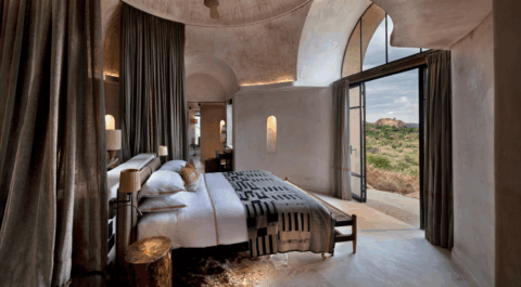 Stilvolles Schlafzimmer mit hohen Gewölbedecken und Blick auf die Landschaft