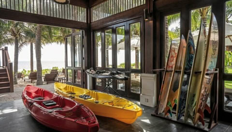 Kajaks und bunte Surfbretter in einem offenen Raum mit Blick aufs Meer