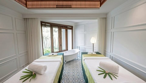 Helles Spa-Zimmer mit zwei Massageliegen und freistehender Badewanne