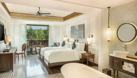 Doppelzimmer mit zwei Betten, hellen Vorhängen und Balkonblick ins Grüne