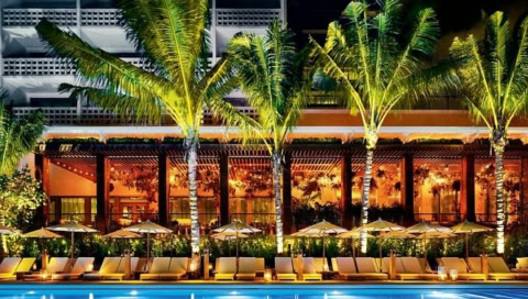 Beleuchteter Pool mit Sonnenliegen