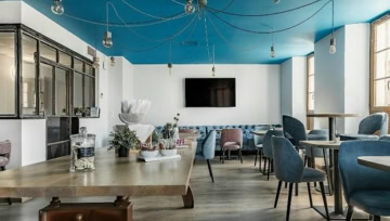 Offener Frühstücksbereich mit Buffet, modernen Sitzmöbeln und markantem blauen Deckendesign im Hotel The Originals Boutique