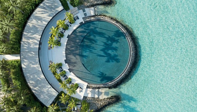 Kreisförmiger Pool des Resorts aus der Vogelperspektive mit Sonnenterrasse und direktem Zugang zur Lagune