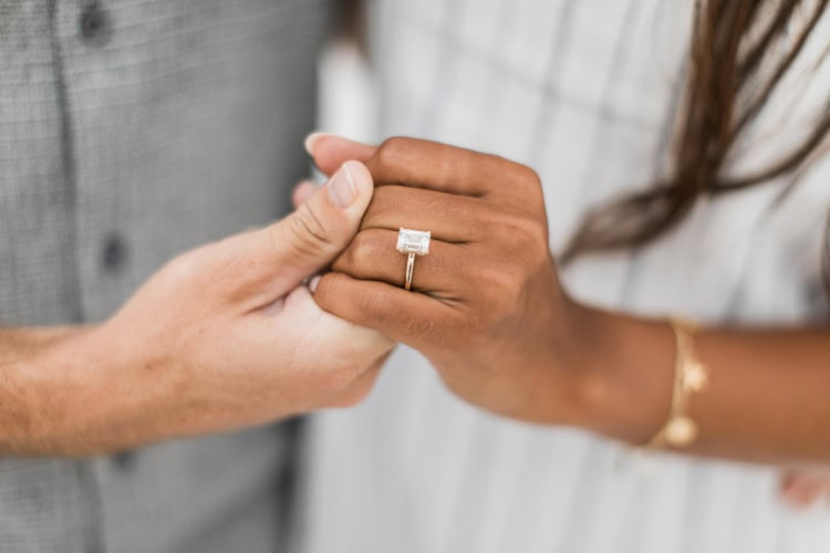 Ein verlobtes Paar hält Hände und der weibliche Partner trägt einen Ring an der linken Hand.