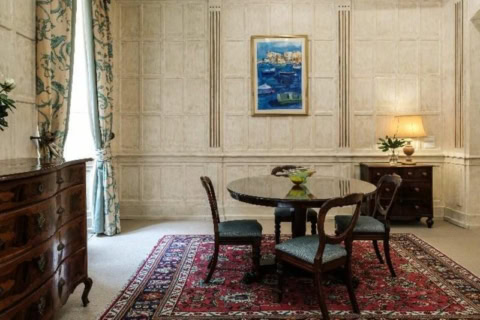 Kleiner Tisch mit Stühlen in einem Raum mit Steinwänden, Teppich und Kommode